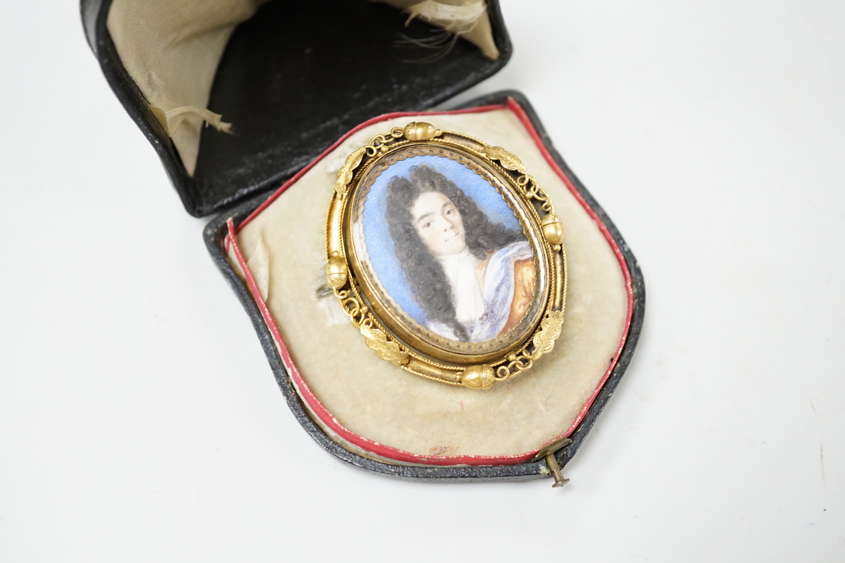 A Georgian yellow metal mounted oval portrait watercolour of a gentleman, with acorn and leaf border, 58mm.